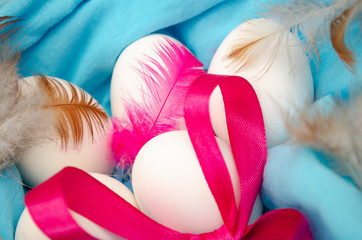 Easter eggs on blue fabric with feathers
