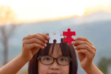 Little child holding piece of blank jigsaw puzzle