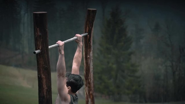 Man doing pullups in heavy rain. Slow motion. 100fps.