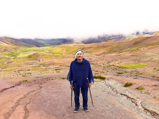 A young male tourist enjoying the view of the incredible Rainbow Mountains outside of Cusco, Peru. The amounts are a variety of colours from the mineral deposits in the soil.