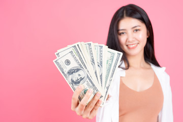 Successful beautiful Asian business young woman holding money US dollar bills in hand on pink background , business concept