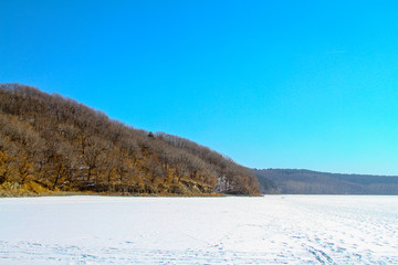 Landscape of frozen lake covered by snow in winter