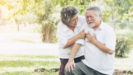 Fototapeta premium Senior male Asian suffering from bad pain in his chest heart attack at garden park , Wife supporting husband - Elderly couple senior heart disease