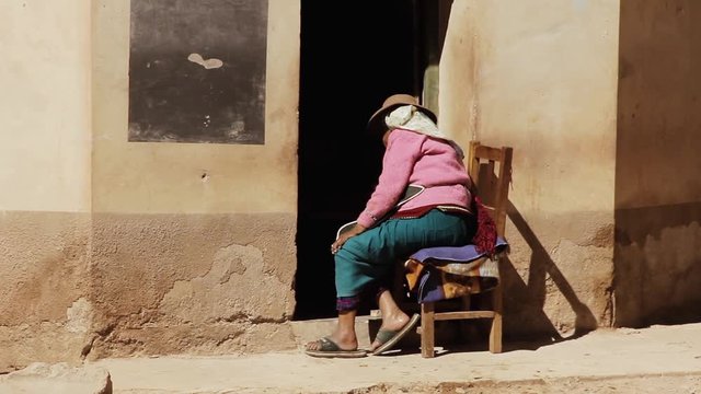Senior Woman sitting at the Entrance of her House in Susques, Jujuy Province, Argentina. Slow Motion. Zoom In.  