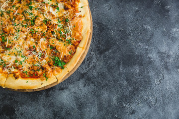 Pizza with bacon, cheese, tomato and basil leaves on dark background. Flat lay, top view