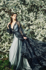 Portrait of a young beautiful fashionable woman in an evening dress . Girl posing in a blooming...