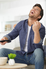 man watching tv making gesture of victory