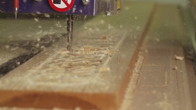 A close up slow motion shot of a CNC machine cutting a timber sign.