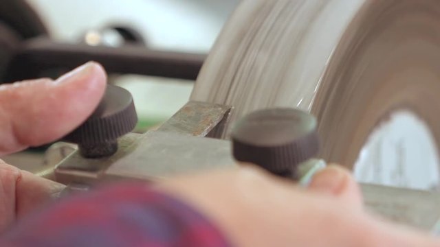 A close up shot of carpenter sharpening a Chisel on a Whetstone in Slow motion