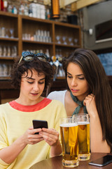 Two girls chatting while having a beer. Long haired and short haired girl drinking beer. 