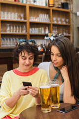 Two girls chatting while having a beer. Long haired and short haired girl drinking beer. 