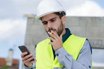 builder talking on phone and smoking a cigarette