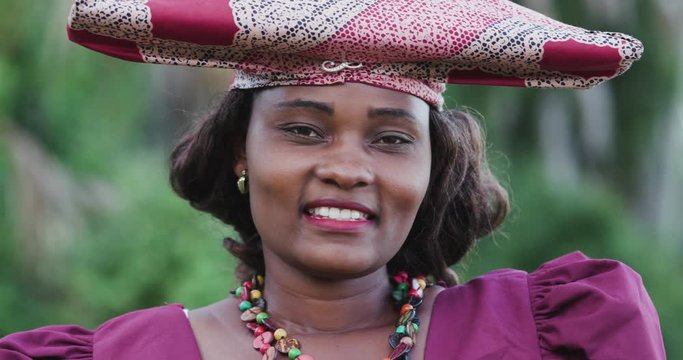 4K close-up portrait of pretty black Herero woman in Traditional Dress looking at the camera 