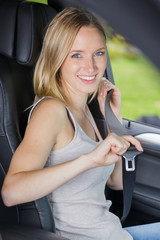 woman fastening seat belt in car