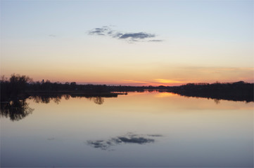 Fototapeta na wymiar Pink-yellow sunset and sun reflection on lake water surface.