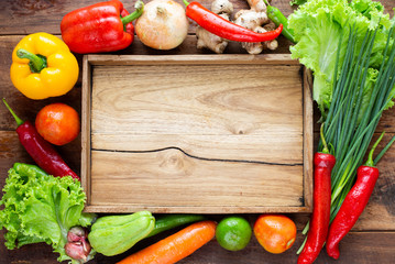 Many kind of vegetable inside and outside wood tray on wood background, for cooking and kitchen concept.