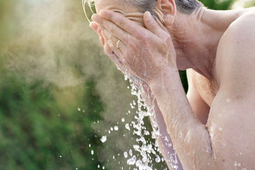 Fototapeta premium Portrait of topless man splashing face with water