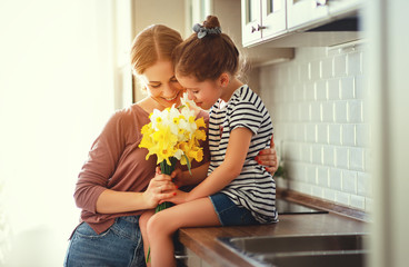 Fototapeta na wymiar happy mother's day! child daughter gives mother a bouquet of flowers to narcissus and gift.
