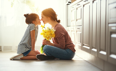 happy mother's day! child daughter   gives mother a bouquet of flowers to narcissus and gift.