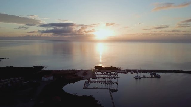 Aerial of a pretty village in Sardinia, Italy. Sunrise on the coast, parking yachts, mountains in the background