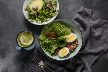Vegan Buddha bowl with buckwheat, avocado, boiled eggs, cucumber, arugula beet leaves. Diet, detox, healthy food concept