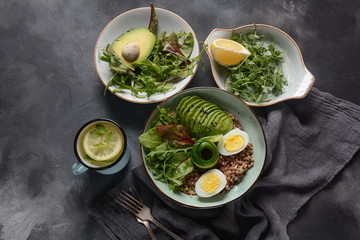 Vegan Buddha bowl with buckwheat, avocado, boiled eggs, cucumber, arugula beet leaves. Diet, detox, healthy food concept