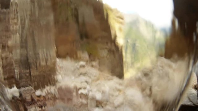 POV animal looks through waterfall on high mountains of Himalaya gray sheer cliffs