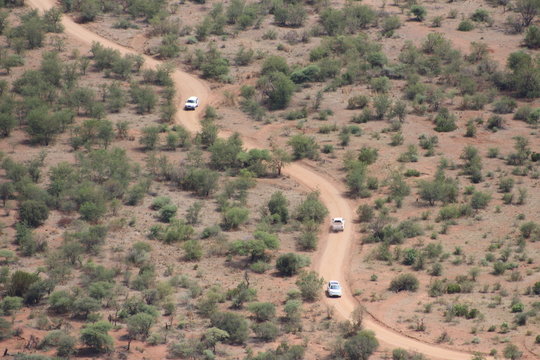 Cars on a dirt road in arid landscape