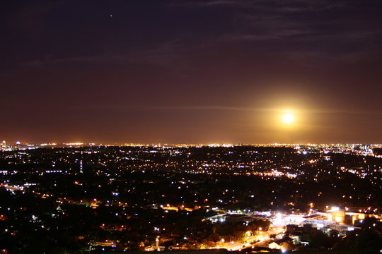 A view of the city at night with misty moon in the sky