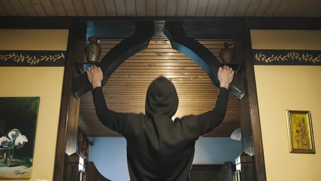Home fitness. Man doing pullups in the living room. Wide grip pullips. 