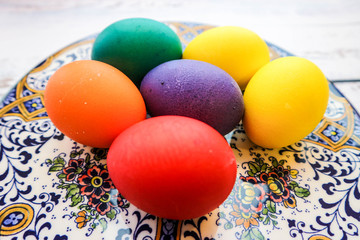 Fototapeta na wymiar Bright colorful easter eggs on vintage ornamental plate on wooden background