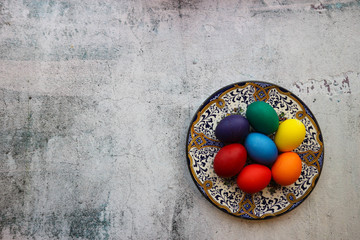 Obraz na płótnie Canvas Colorful bright easter eggs on the beautiful ornamental painted plate on wooden background