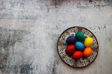 Colorful bright easter eggs on the beautiful ornamental painted plate on wooden background
