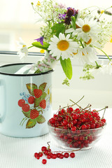 A bouquet of wildflowers and a glass bowl of red currant