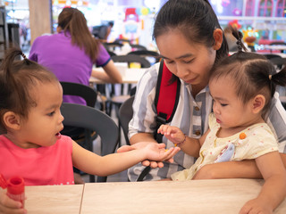 Obraz premium Asian little girl sharing candy for her sister at food court in the mall.