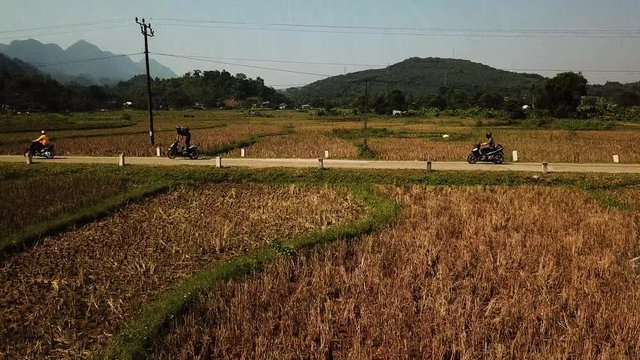 Motorcycles riding through rural road in Hanoi, Vietnam. Aerial tracking shot