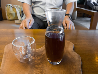 An empty glass and a glass bottle filled with coffee.