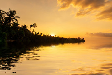 Fototapeta na wymiar Beautiful sunset on the beach with palms on a Caribbean island