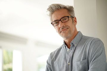 Portrait of handsome mature man wearing glasses smiling at camera