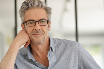 Portrait of handsome mature man wearing glasses smiling at camera