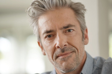 Portrait of handsome mature man looking at camera in contemporary home