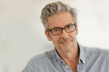 Portrait of handsome mature man wearing glasses smiling at camera