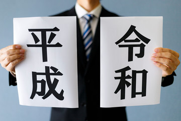 平成と令和を見せるスーツの男性