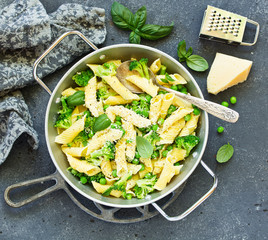 penne pasta with spinach pesto sauce, green peas and broccoli, top view