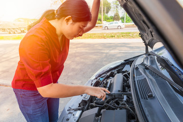 Asian teen girl open car hood to checking engine oil fix breakdown problem.