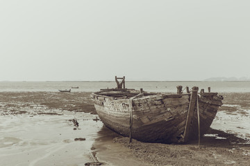 old wooden wreck ship on dried tide sea .shipwreck vintage color tone.