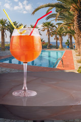 a glass of cold drink on the table of the beach cafe against the background of the pool, palm trees and the sea