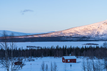 Red house of Aktse in the snow, with view toward National Park Sarek. Lapland, Sweden.