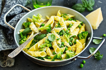 penne pasta with spinach pesto sauce, green peas and broccoli, top view