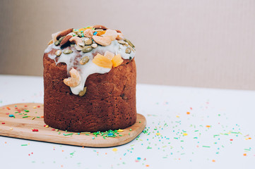 Selective focus close up image of delicious homemade Easter cake freshly baked, multicolored sweet sprinkles, on white table. Easter, birthday, family event celebrating concept